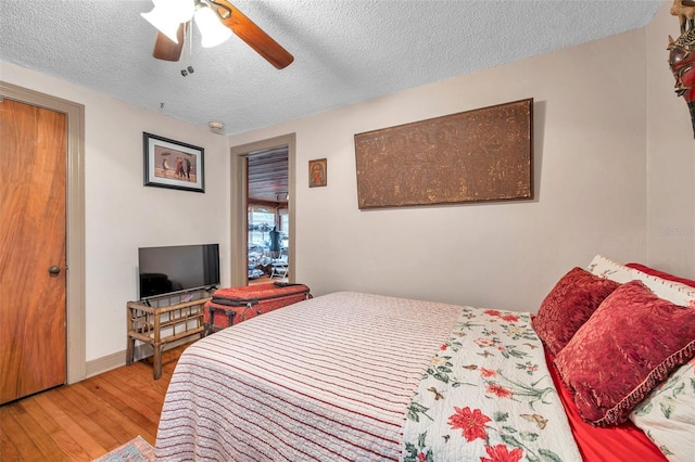 bedroom featuring light wood-type flooring, a textured ceiling, and ceiling fan