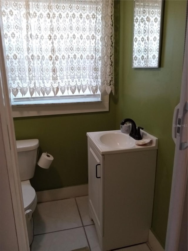 bathroom with a healthy amount of sunlight, vanity, toilet, and tile patterned flooring