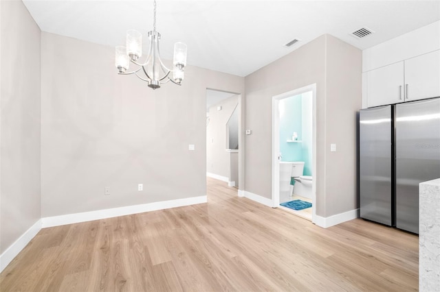 unfurnished dining area featuring a chandelier and light hardwood / wood-style floors