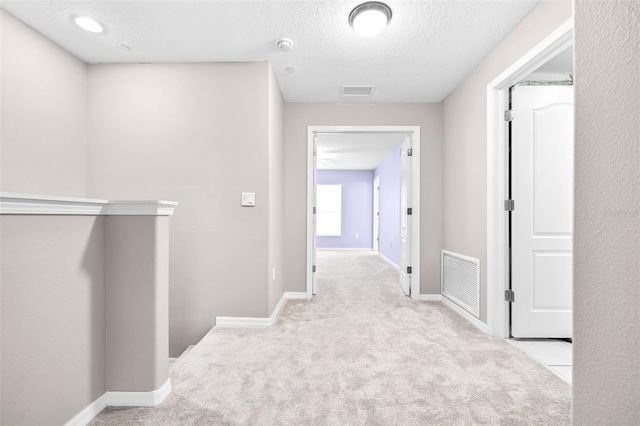 hallway featuring light carpet and a textured ceiling