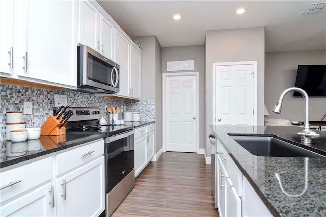 kitchen featuring white cabinetry, sink, dark stone counters, and appliances with stainless steel finishes