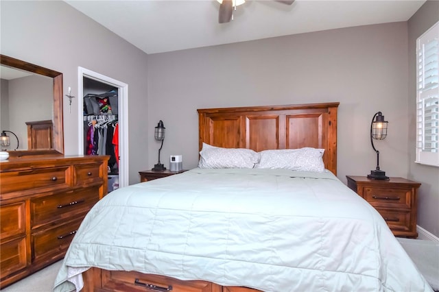 bedroom featuring ceiling fan, light colored carpet, a closet, and a walk in closet