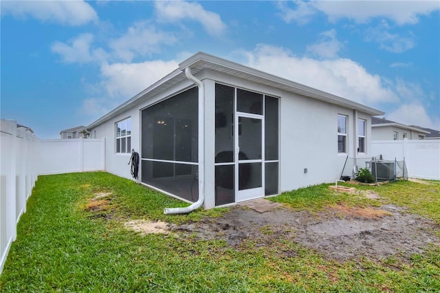 back of house with central AC, a lawn, and a sunroom