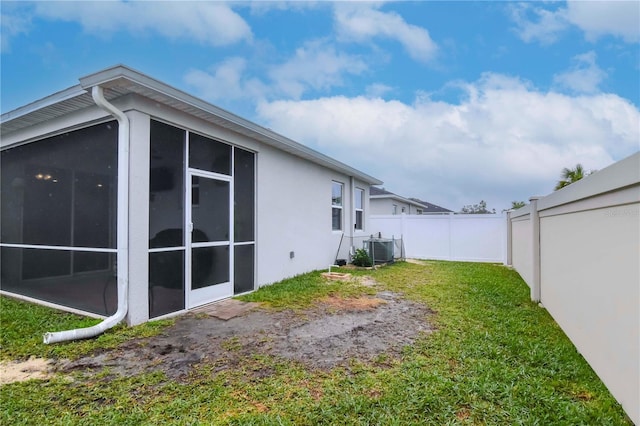 view of yard featuring central AC unit and a sunroom