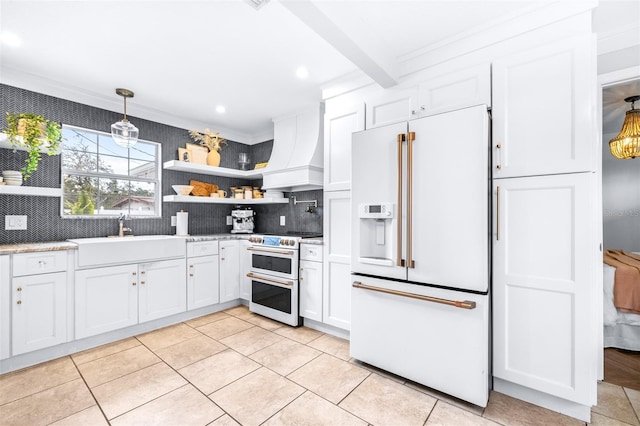 kitchen featuring premium range hood, sink, high end appliances, hanging light fixtures, and white cabinets