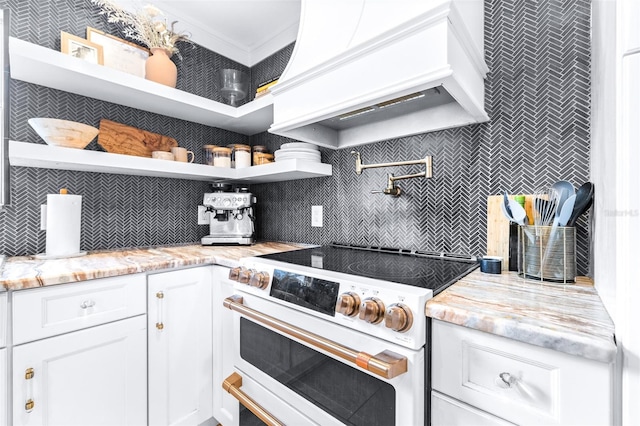 kitchen with tasteful backsplash, light stone countertops, high end white range oven, and custom exhaust hood