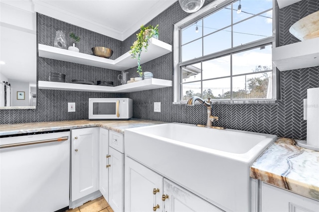 kitchen with sink, backsplash, white cabinets, light tile patterned floors, and white appliances