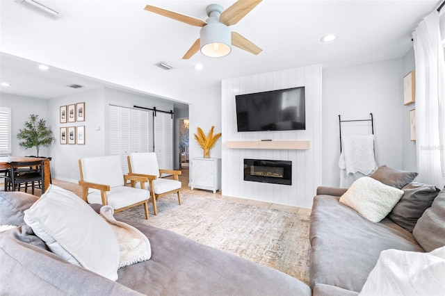 living room with a large fireplace and ceiling fan