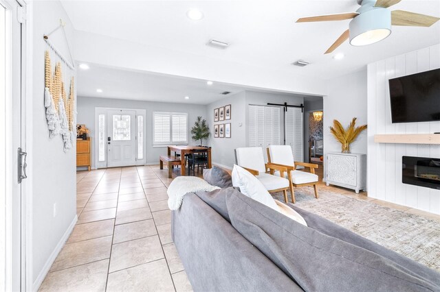 tiled living room with ceiling fan and a fireplace