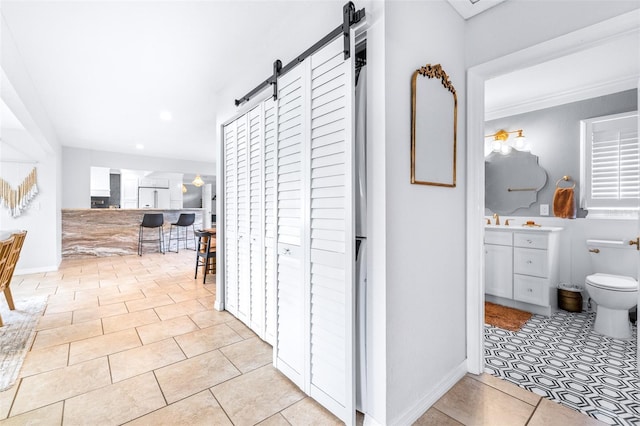 hallway with a barn door, sink, and light tile patterned floors