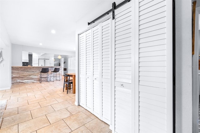 hallway with light tile patterned floors and a barn door