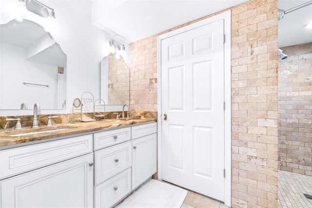 bathroom with vanity, tile patterned floors, a shower, and brick wall