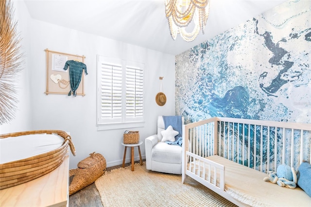 bedroom with a nursery area and hardwood / wood-style floors