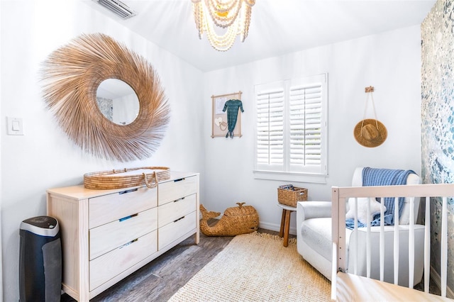 bedroom featuring dark hardwood / wood-style floors and a nursery area