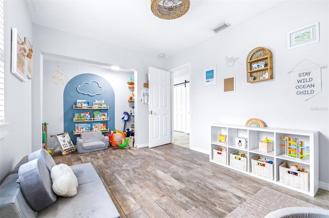 game room with wood-type flooring and a barn door