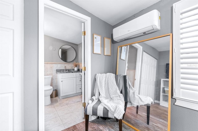 bathroom featuring an AC wall unit, hardwood / wood-style floors, tile walls, vanity, and toilet