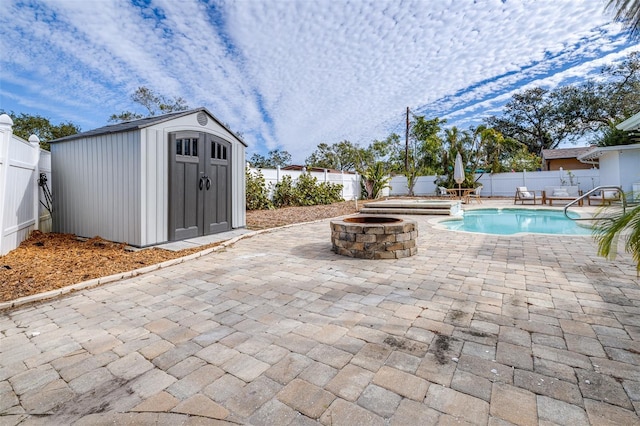 view of pool featuring a storage shed, a patio area, and an outdoor fire pit