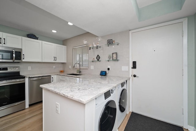 kitchen featuring sink, light hardwood / wood-style flooring, appliances with stainless steel finishes, white cabinetry, and kitchen peninsula