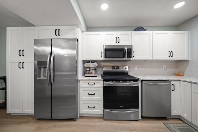 kitchen featuring white cabinetry, light stone countertops, stainless steel appliances, and light hardwood / wood-style floors