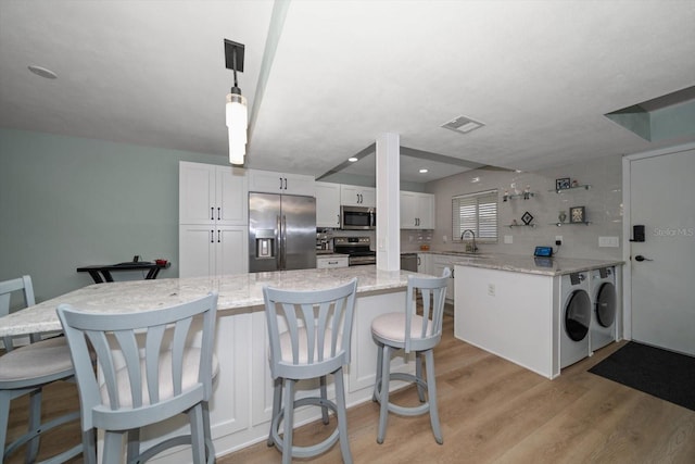 kitchen with stainless steel appliances, decorative light fixtures, light stone countertops, and white cabinets