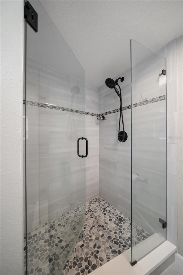 bathroom with a textured ceiling and a shower with shower door