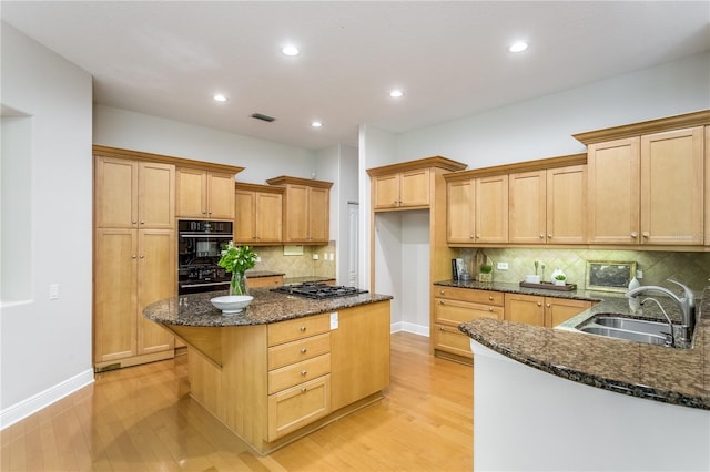 kitchen featuring dark stone counters, sink, light hardwood / wood-style flooring, and black appliances