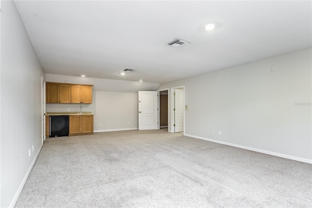 unfurnished living room featuring wet bar and light colored carpet