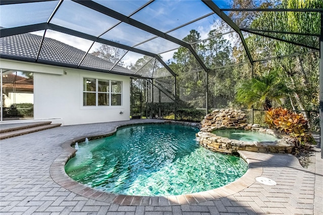 view of swimming pool with an in ground hot tub, glass enclosure, and a patio