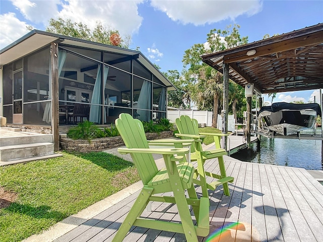 wooden deck with a sunroom, a boat dock, and a lawn