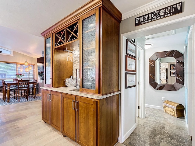 bar featuring lofted ceiling, sink, ornamental molding, and light hardwood / wood-style floors