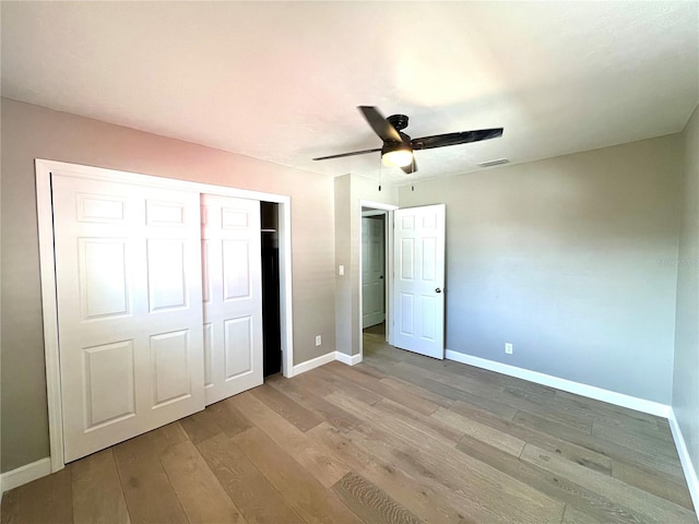 unfurnished bedroom featuring ceiling fan, light hardwood / wood-style floors, and a closet