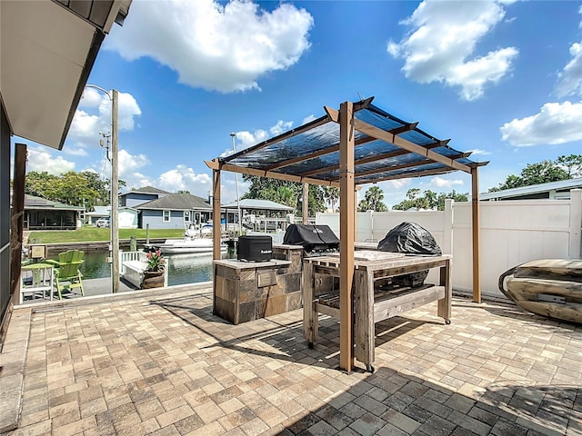 view of patio / terrace with a water view, a grill, an outdoor kitchen, and a pergola