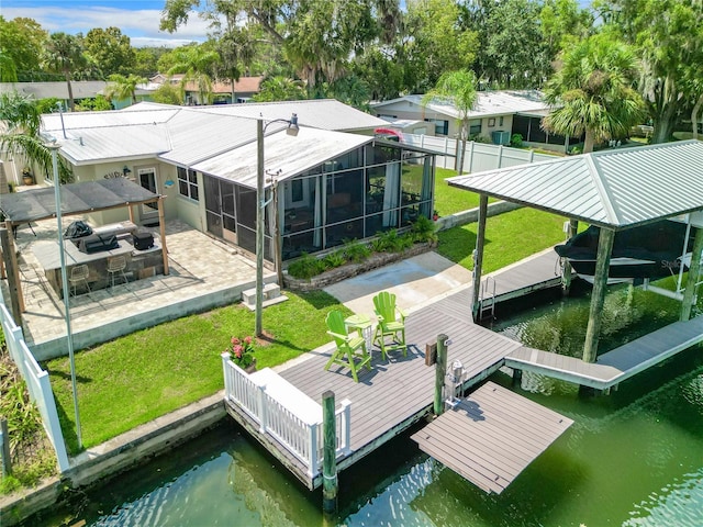 view of dock with a yard, a patio area, a water view, and glass enclosure