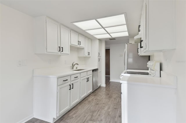 kitchen with dishwasher, sink, white cabinets, stove, and light hardwood / wood-style floors