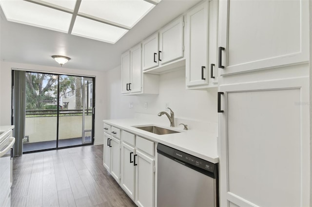 kitchen with stainless steel dishwasher, wood-type flooring, sink, and white cabinets