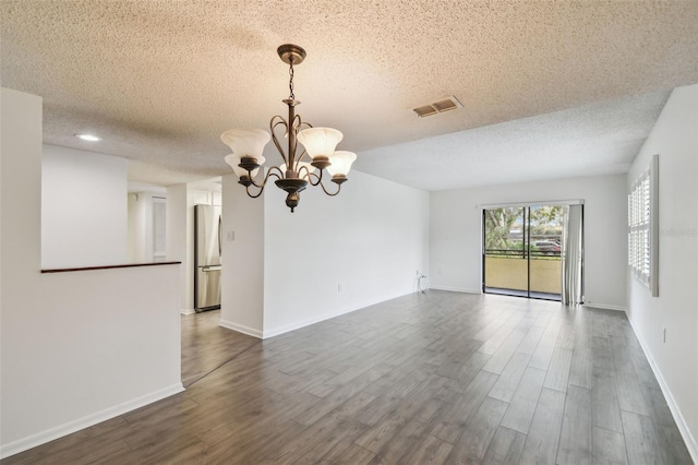 unfurnished room with a notable chandelier, dark hardwood / wood-style floors, and a textured ceiling