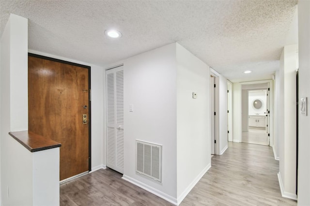 foyer with a textured ceiling and light hardwood / wood-style floors