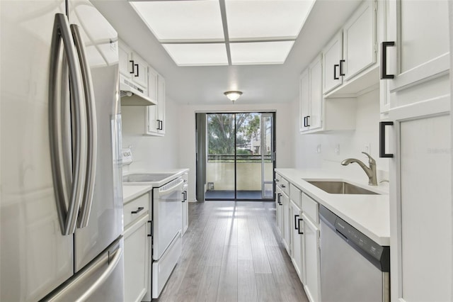 kitchen with sink, wood-type flooring, stainless steel appliances, and white cabinets