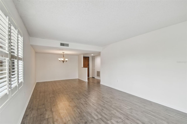 spare room featuring hardwood / wood-style flooring, a textured ceiling, and a chandelier