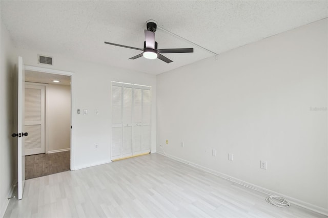 unfurnished bedroom featuring a textured ceiling, light hardwood / wood-style flooring, a closet, and ceiling fan