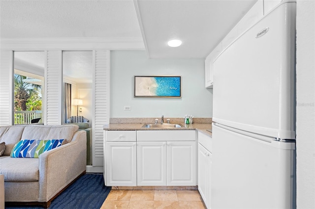 kitchen featuring light tile patterned flooring, sink, white cabinetry, ornamental molding, and white fridge