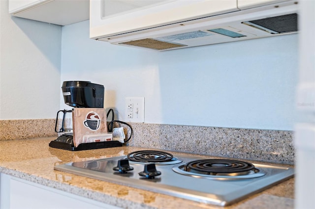 details featuring white cabinetry, electric stovetop, extractor fan, and light stone counters