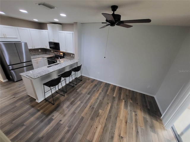 kitchen with stainless steel fridge, electric range oven, a kitchen breakfast bar, white cabinets, and kitchen peninsula