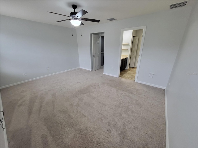 unfurnished bedroom with ceiling fan, ensuite bath, and light carpet