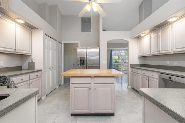 kitchen with white cabinetry, wood counters, appliances with stainless steel finishes, and a high ceiling