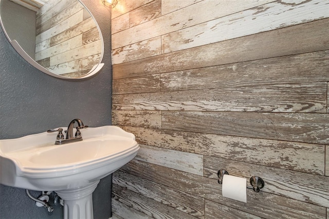 bathroom featuring sink and wood walls