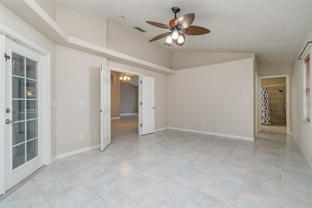 tiled empty room with vaulted ceiling, a textured ceiling, and ceiling fan