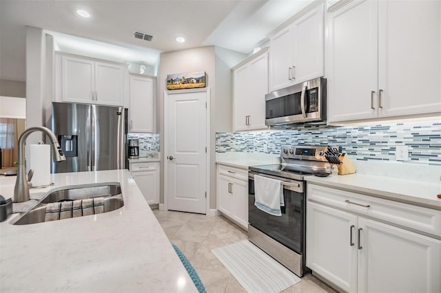 kitchen with white cabinetry, appliances with stainless steel finishes, sink, and light stone counters