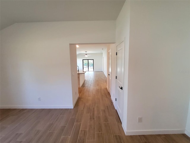 hallway featuring light hardwood / wood-style flooring and vaulted ceiling