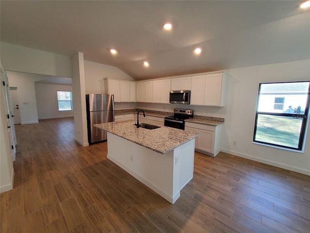 kitchen featuring lofted ceiling, a center island with sink, stainless steel appliances, light stone countertops, and white cabinets